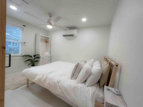 1 dormitorio blanco con 1 cama y ventilador de techo en The Shire 255 D - Solitude - Downtown, en Southern Pines