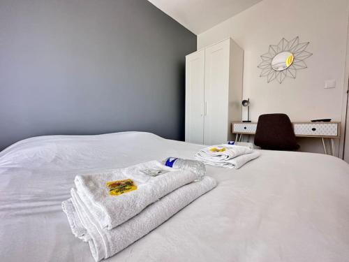 une chambre avec un lit blanc avec des serviettes dessus dans l'établissement Henri/ 3 chambres vue sur le canal et la basilique, à Reims