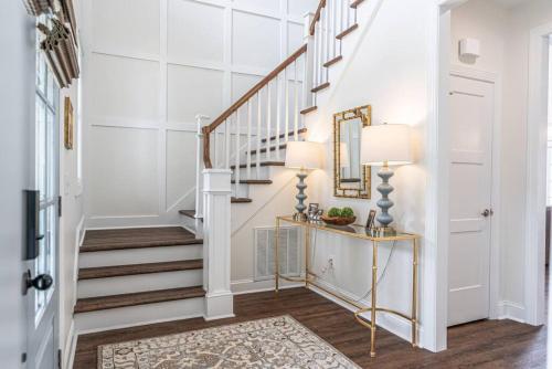 a hallway with white walls and stairs with a mirror at Sleeps 6-Southern Pines in Southern Pines