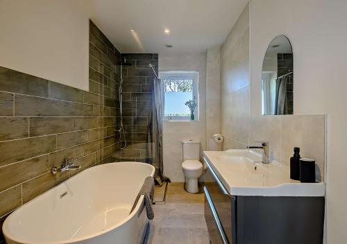 a bathroom with a tub and a sink and a toilet at No 6 Deer Glade in Sparham