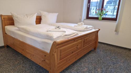 una cama de madera con sábanas blancas y toallas. en Markt 9 Appartements Oberwiesenthal, en Kurort Oberwiesenthal
