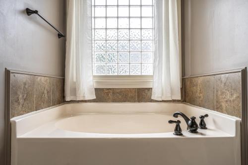 a bath tub with two faucets and a window at Sleeps 8- in Carthage in Carthage