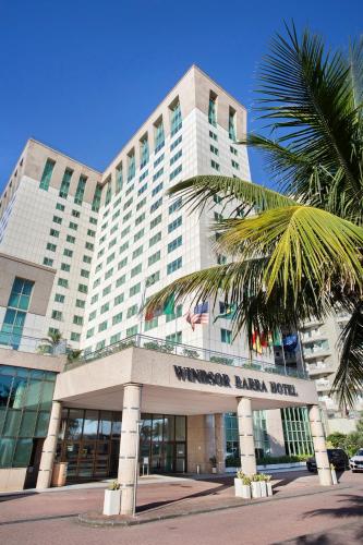 a large building with a palm tree in front of it at Windsor Barra Hotel in Rio de Janeiro