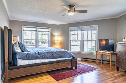 a bedroom with a bed and a tv and windows at Sleeps 6- Whispering Pines Lakefront 