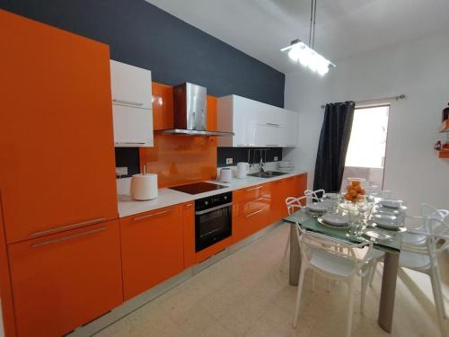 una cucina con armadi arancioni e tavolo con sedie di Tal-Munfuha- Centrally Located Space. a La Valletta