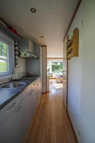 a kitchen with a sink and a wooden floor at Chalet voorzien van alle gemakken in een bosrijke omgeving in Voorthuizen