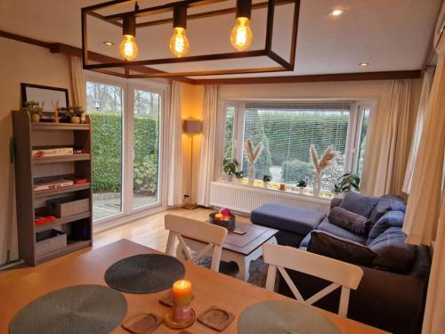 a living room with a table and a couch at Chalet voorzien van alle gemakken in een bosrijke omgeving in Voorthuizen