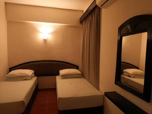a hotel room with two beds and a mirror at 3 BEDROOM SEAVIEW CONDO @ GLORY BEACH RESORT, PORT DICKSON in Port Dickson