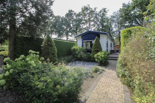 a small white house with a blue roof in a garden at Chalet voorzien van alle gemakken in een bosrijke omgeving in Voorthuizen