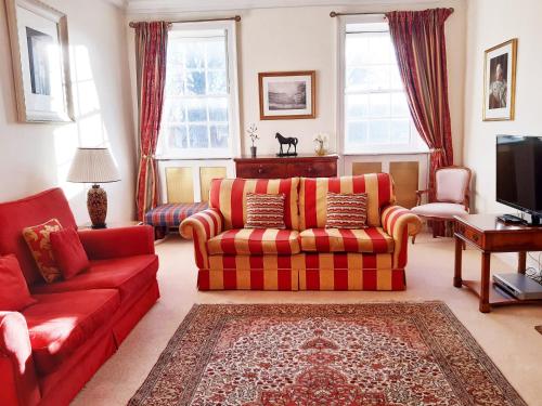 a living room with red couches and a tv at 18 The Circus Apartment in Bath