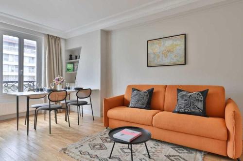 un salon avec un canapé orange et une table dans l'établissement Modern apartment - 1BR-4P - Canal St-Martin, à Paris