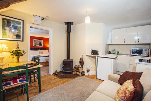 a living room with a table and a kitchen with a stove at Cosy Stable at Oak Farm in Usk