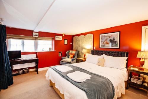 a bedroom with red walls and a bed and a desk at Cosy Stable at Oak Farm in Usk