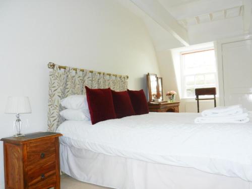 a bedroom with a large white bed with red pillows at 18 The Circus Apartment in Bath