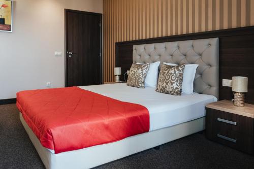 a bedroom with a large bed with a red blanket at Business Hotel Plovdiv - Central Location in Plovdiv