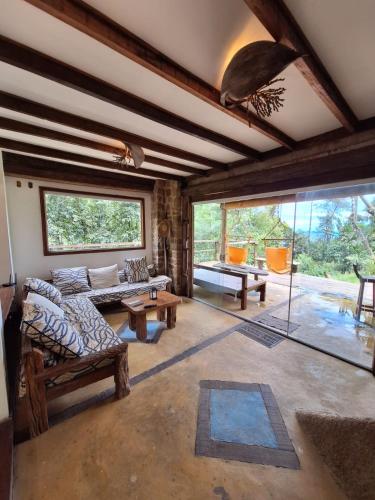a living room with couches and tables and windows at Chalé dos Altos de Laranjeiras in Paraty