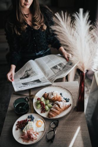 a woman sitting at a table with plates of food at Business Hotel Plovdiv - Central Location in Plovdiv