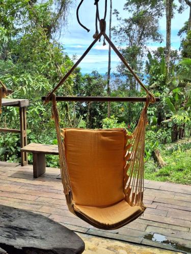 an orange chair hanging in a hammock on a patio at Chalé dos Altos de Laranjeiras in Paraty