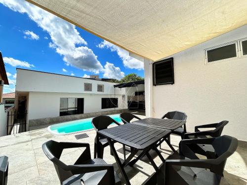 un patio con mesa, sillas y piscina en Casa Temporada Rio Quente (Em frente ao Hot Park) in 