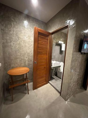 a bathroom with a wooden door and a table and a sink at RL Harbor Inn in El Nido