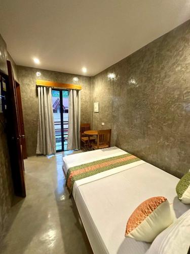 a bedroom with two beds and a table and a window at RL Harbor Inn in El Nido
