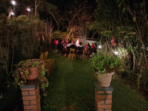 a group of people sitting at a table in a garden at night at Pear Tree Entire 2BHK Villa Kotagiri in Kotagiri