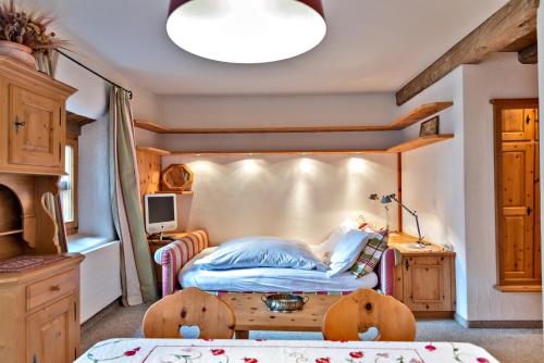 Dormitorio pequeño con cama y mesa en Chesa Grischuna - Madulain, en Madulain