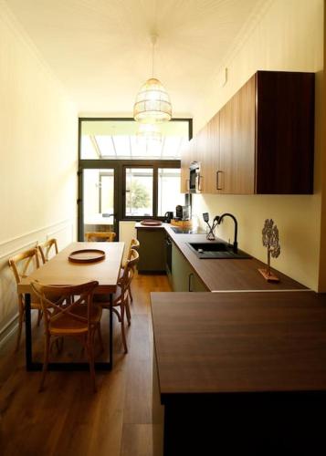 une cuisine avec une table et un évier et une table et des chaises dans l'établissement L'arbre d'or Appart hyper centre spa couvert, à Cambrai