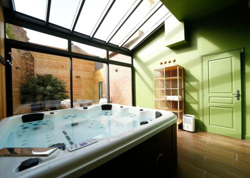 une grande baignoire dans une pièce avec une grande fenêtre dans l'établissement L'arbre d'or Appart hyper centre spa couvert, à Cambrai