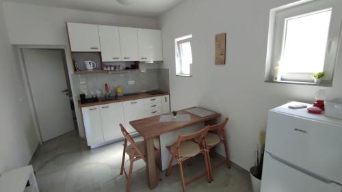 a kitchen with a table and chairs and a refrigerator at Apartment with Terrace and Garden in Pirovac