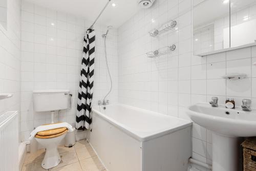 La salle de bains blanche est pourvue de toilettes et d'un lavabo. dans l'établissement The Clapham Villas, à Londres