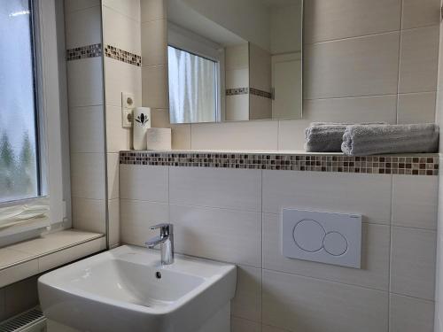 Baño blanco con lavabo y espejo en Haus zur Dünenbake - Apartment 24, en Sankt Peter-Ording