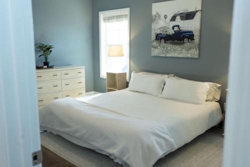 Un dormitorio con una cama blanca y un coche viejo en Sleeps 9- In Whispering Pines, en Carthage