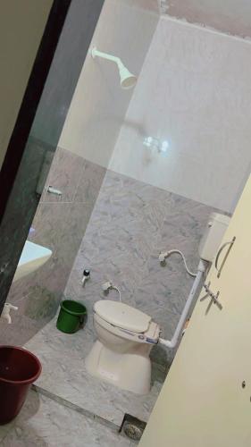 a bathroom with a toilet and a glass wall at Ghanshyam hotel in Dwarka