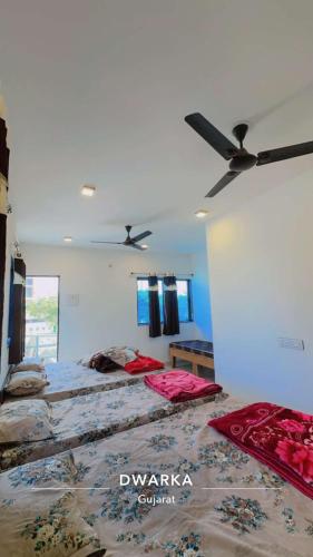 a bedroom with two beds and a ceiling fan at Ghanshyam hotel in Dwarka