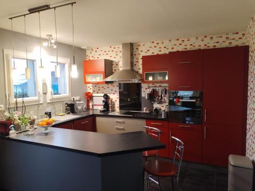une cuisine avec des placards rouges et un comptoir noir dans l'établissement OMAHA-BEACH maison cosy, à Saint-Laurent-sur-Mer