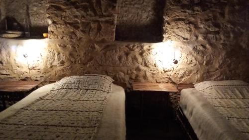 1 dormitorio con 2 camas en una pared de piedra en مراقي سيوة Maraqi Siwa, en Siwa