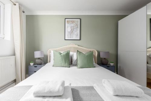 - une chambre avec un grand lit blanc et des oreillers verts dans l'établissement The Clapham Villas, à Londres