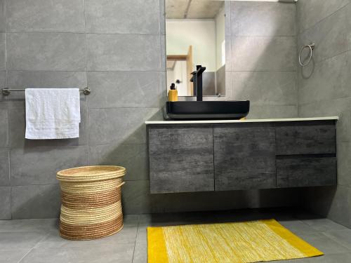 La salle de bains est pourvue d'un lavabo noir et d'un tapis jaune. dans l'établissement Cosy 2 bedrooms apts in Pereybere -Seasons Break Apartment, à Pereybere