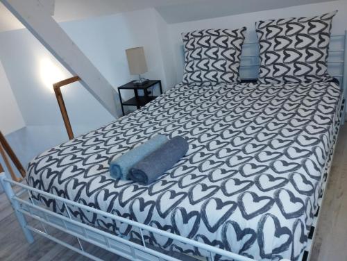 a bed with a black and white comforter at Appartement 1, jardin, collation, 5 min de l'aéroport CDG in Le Mesnil-Amelot