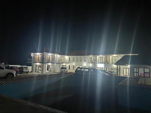 a building with cars parked in a parking lot at night at Ngqamakwe Luxury Guest House and Conference Centre in Nqamakwe