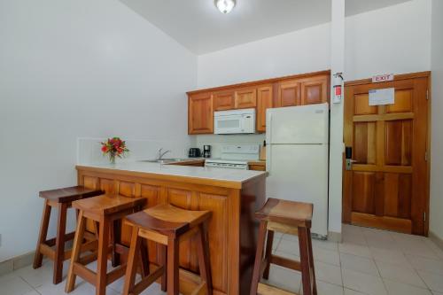 a kitchen with a white refrigerator and wooden cabinets at Best Western Grand Baymen Gardens in San Pedro