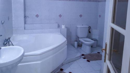 a white bathroom with a toilet and a sink at Luxury apartment in the city center in Tírnavos