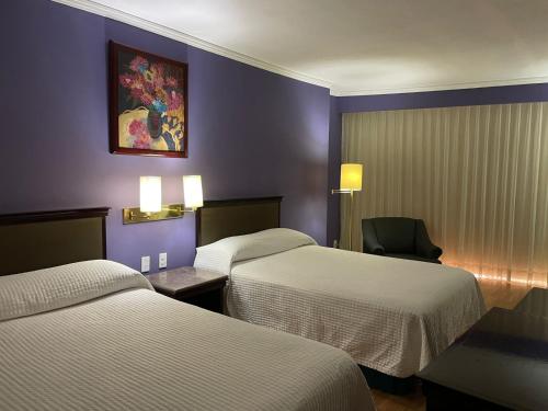 a hotel room with two beds and a chair at Hotel Arroyo de la Plata in Zacatecas