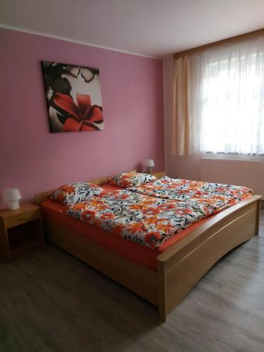 een slaapkamer met een bed met een bloemschilderij aan de muur bij Apartmán Jáchymov Krušné hory in Jáchymov