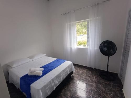 a bedroom with a bed and a fan and a window at Pousada Styllus Miguel Pereira in Miguel Pereira