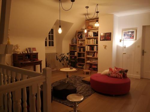 een woonkamer met een rode poef en een trap bij Maison et Florescence in Nuits-Saint-Georges