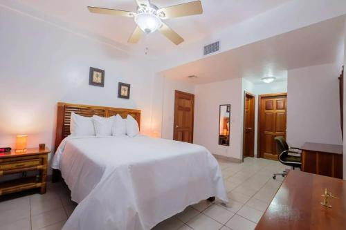 a bedroom with a white bed and a ceiling fan at Best Western Grand Baymen Gardens in San Pedro