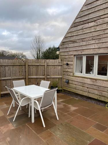 a table and chairs in front of a wooden fence at Honeysuckle Cottage -PART OF ALTON COTTAGES in Alton