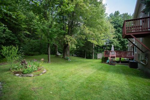 un patio con un árbol y una terraza en 14mi to Mt. Snow! Arcade, Private Suite, King Bed!, en Whitingham